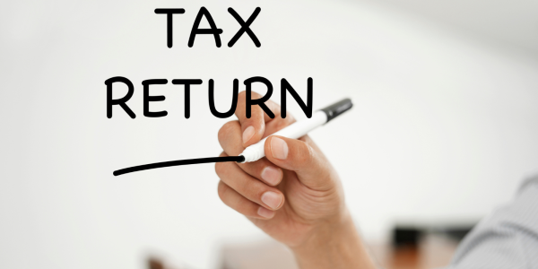 A clear writing board with the words 'TAX RETURN' written in black pen.
