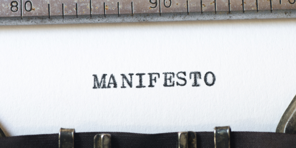 A sheet of paper in a typewriter with the word 'MANIFESTO' typed on it. 