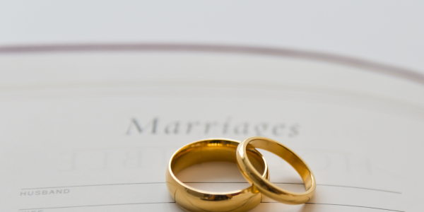 2 wedding bands sat on top of a paper with the word 'Marriages' written at the top.