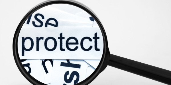 A magnifying glass hovering over the word 'PROTECT'